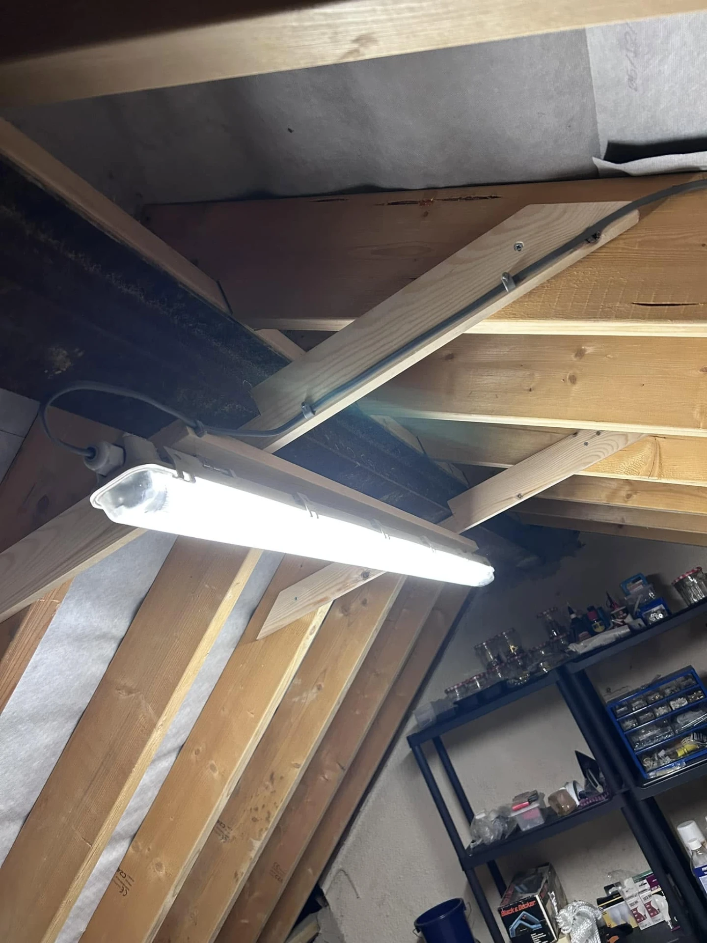 Energy-efficient LED batten light installed between timber roof joists during electrical work